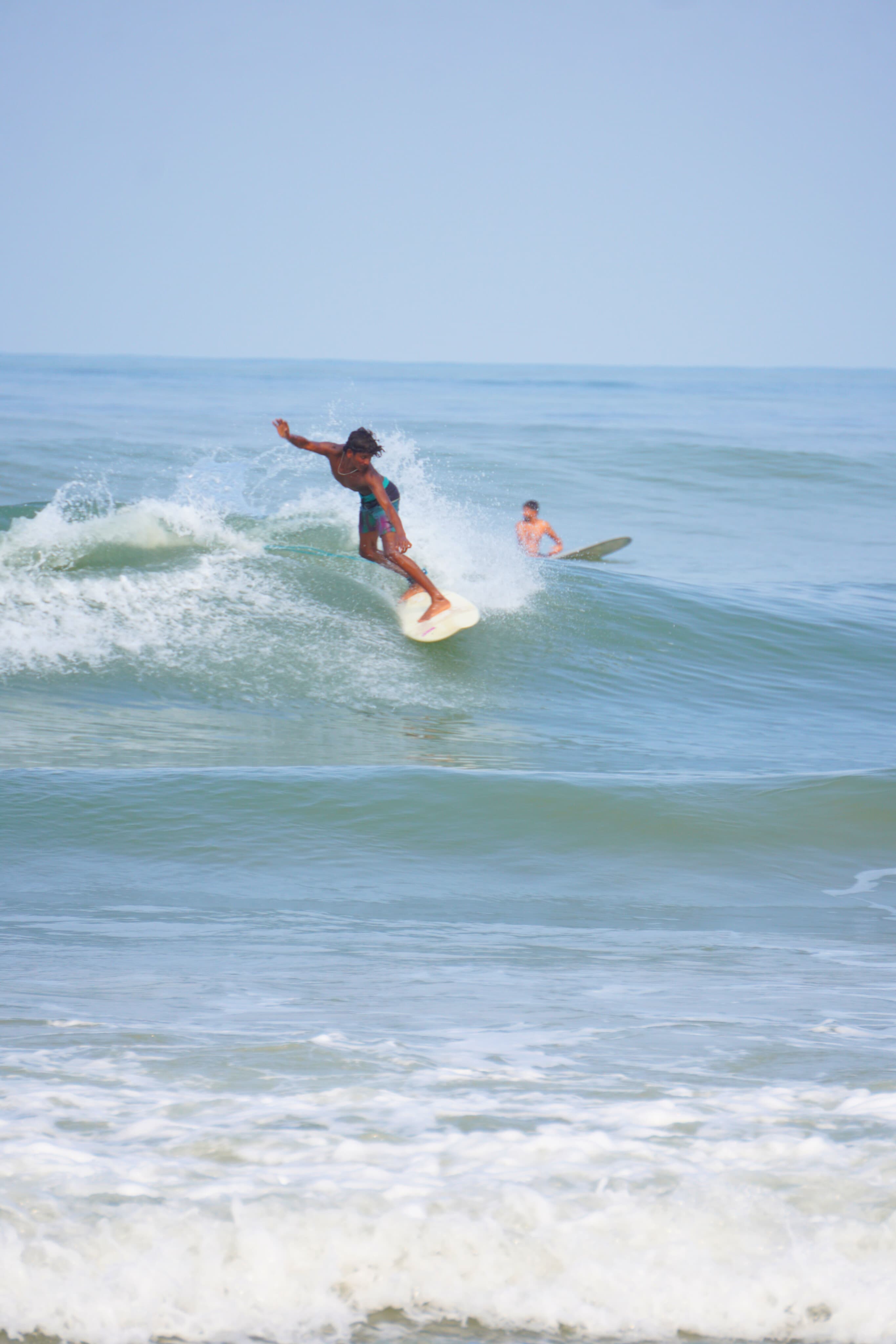 Surfers riding perfect waves at Kapu Beach during golden hour sunset