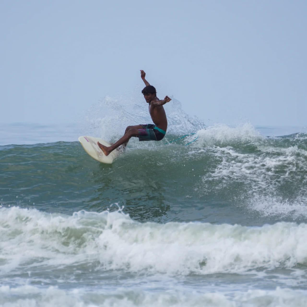 Group of surf school students learning basic techniques on the beach with instructor