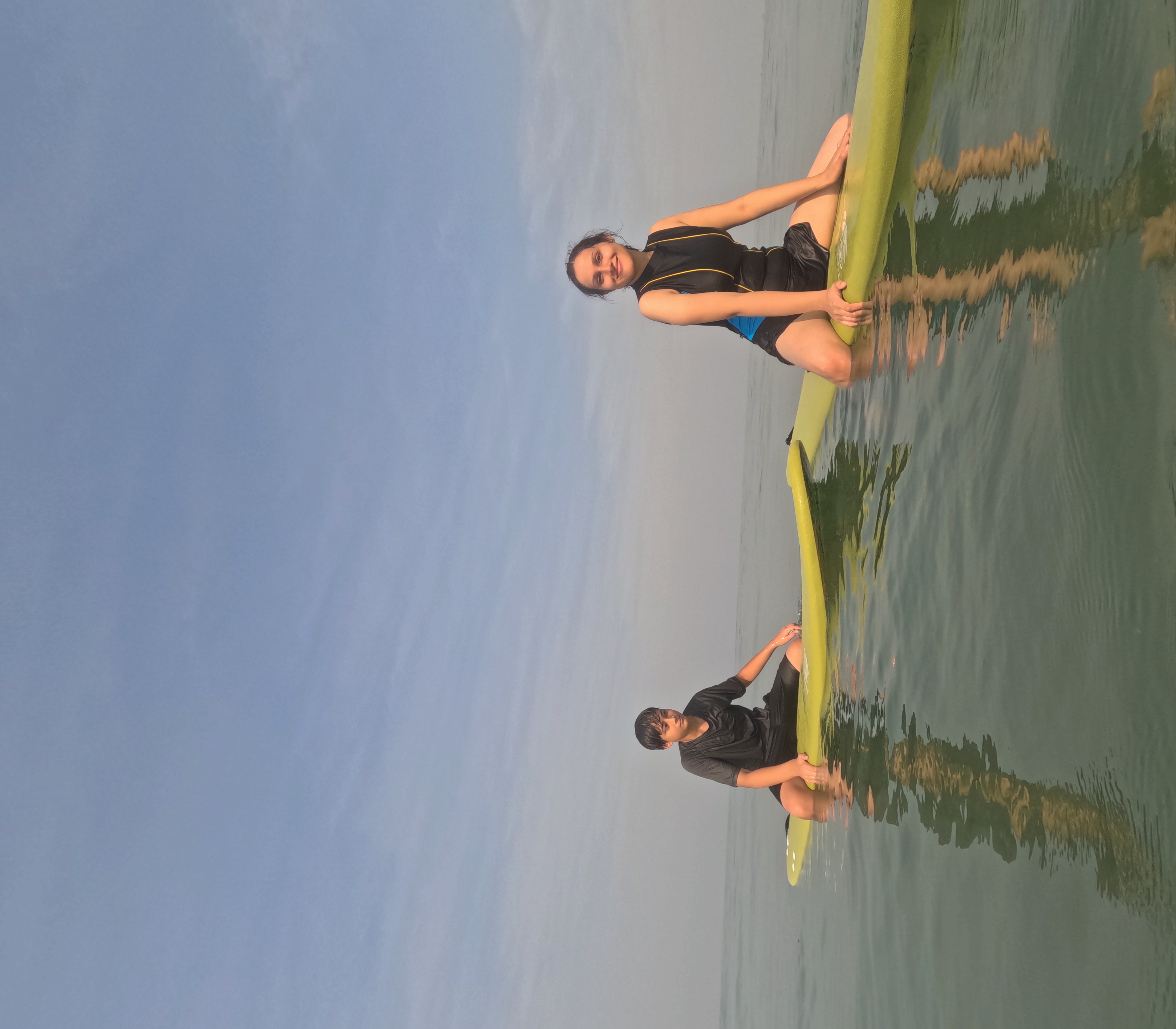 Group of students practicing surfing in ocean waves with instructor supervision